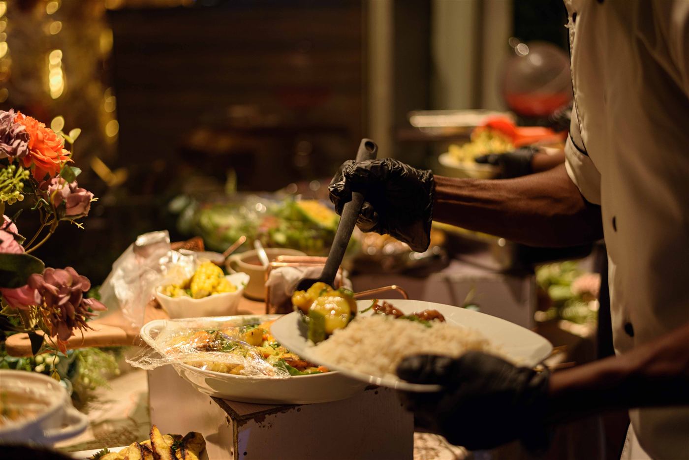 Catering staff serving rice and vegetables from a buffet line at a Cleveland event